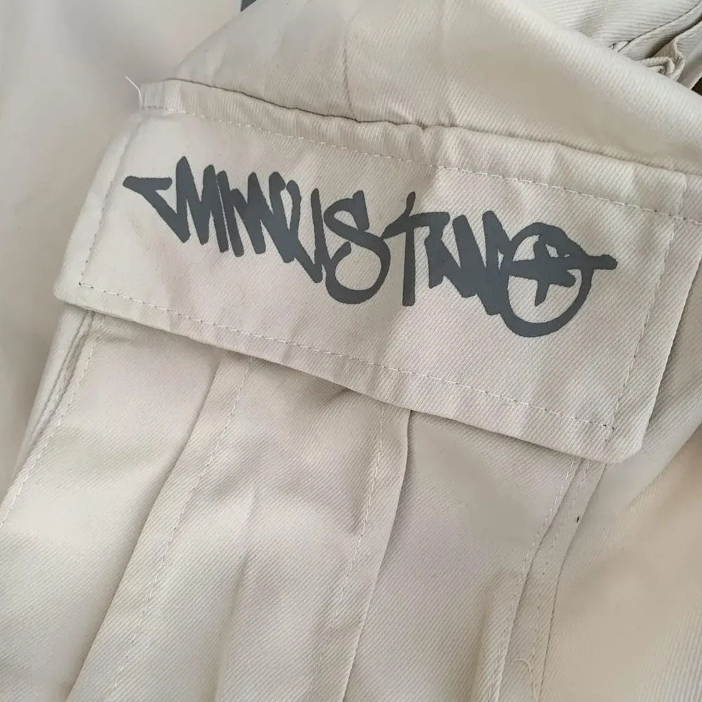 Close-up of beige pants with a black logo on the pocket