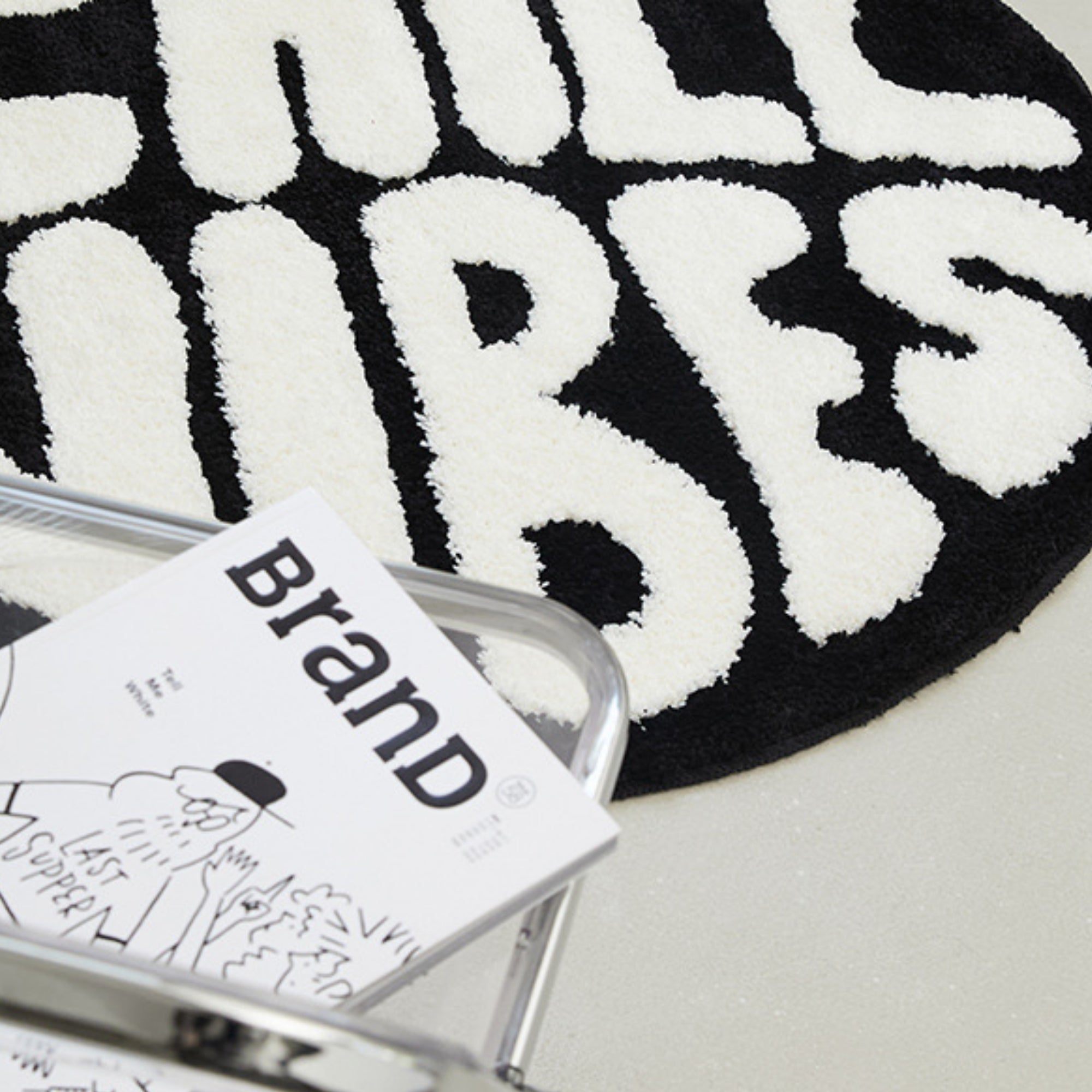 Black and white rug with 'Hill Tribes' branding, featuring a book on top.