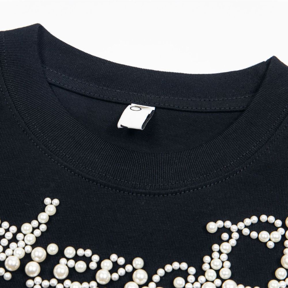 Black shirt with pearl embellishments on a white background