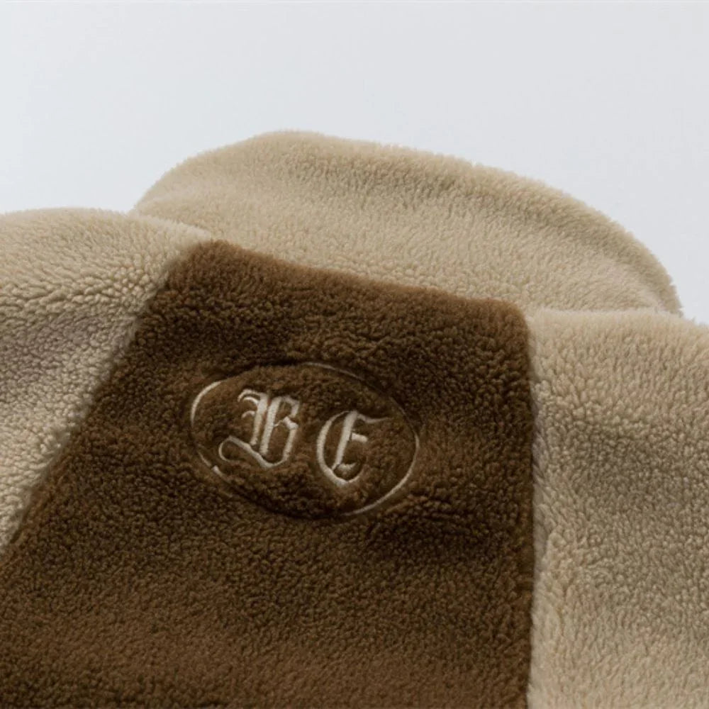 Close-up of a textured fabric surface with a monogrammed logo on a light gray background