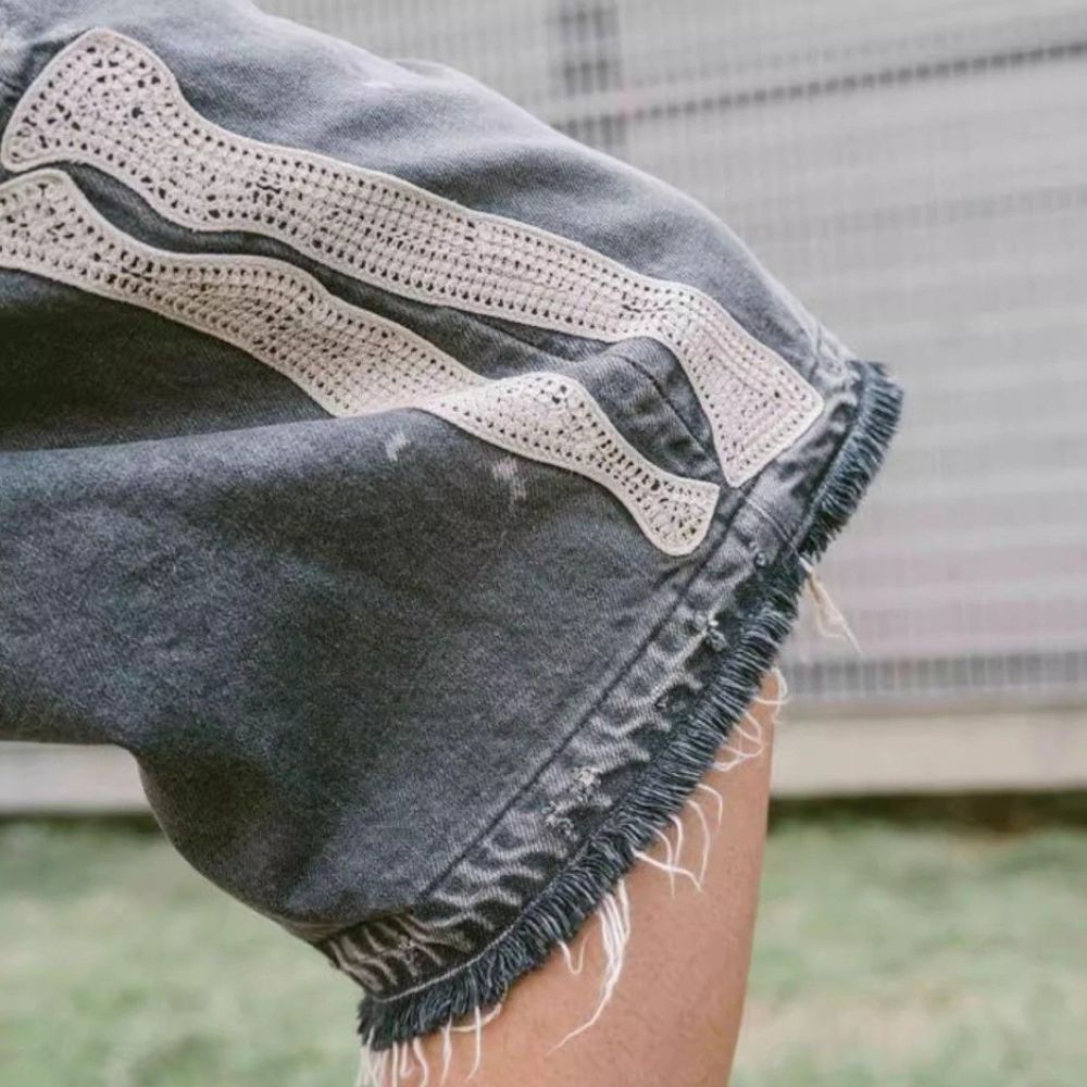 Close-up of denim shorts with lace trim and frayed edges.