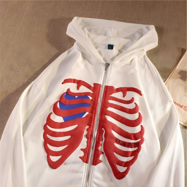 White hoodie with red ribcage design on a beige surface