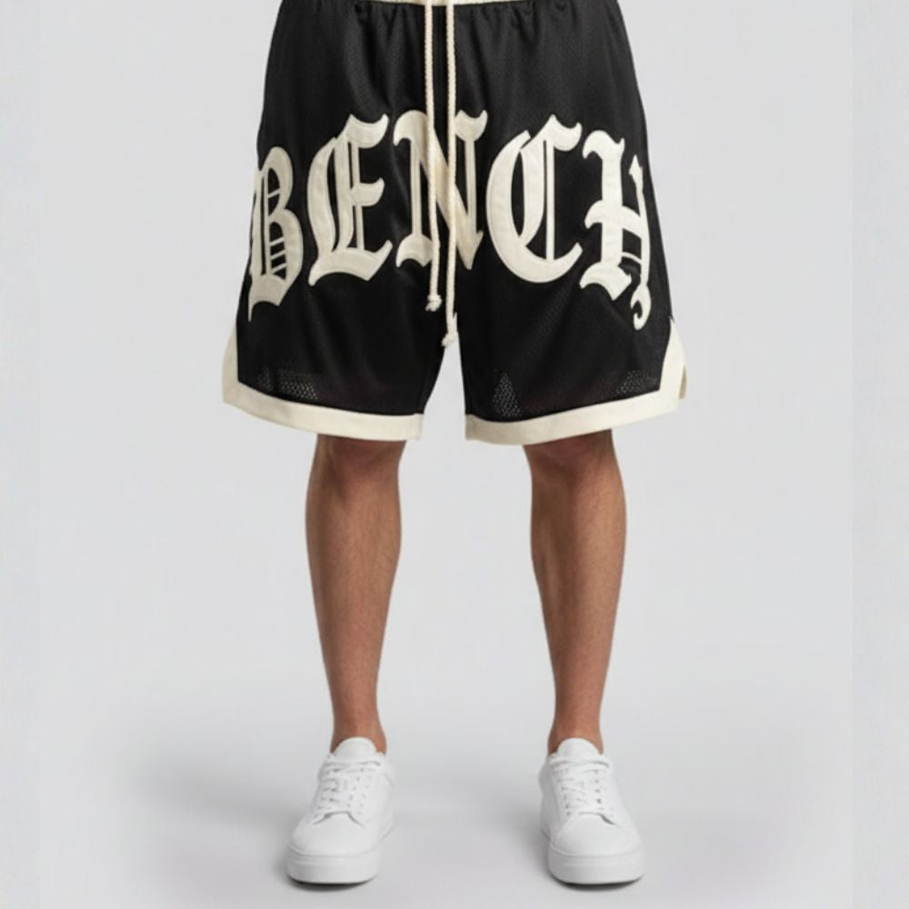 Black shorts with 'BENCH' branding worn by a person on a light gray background
