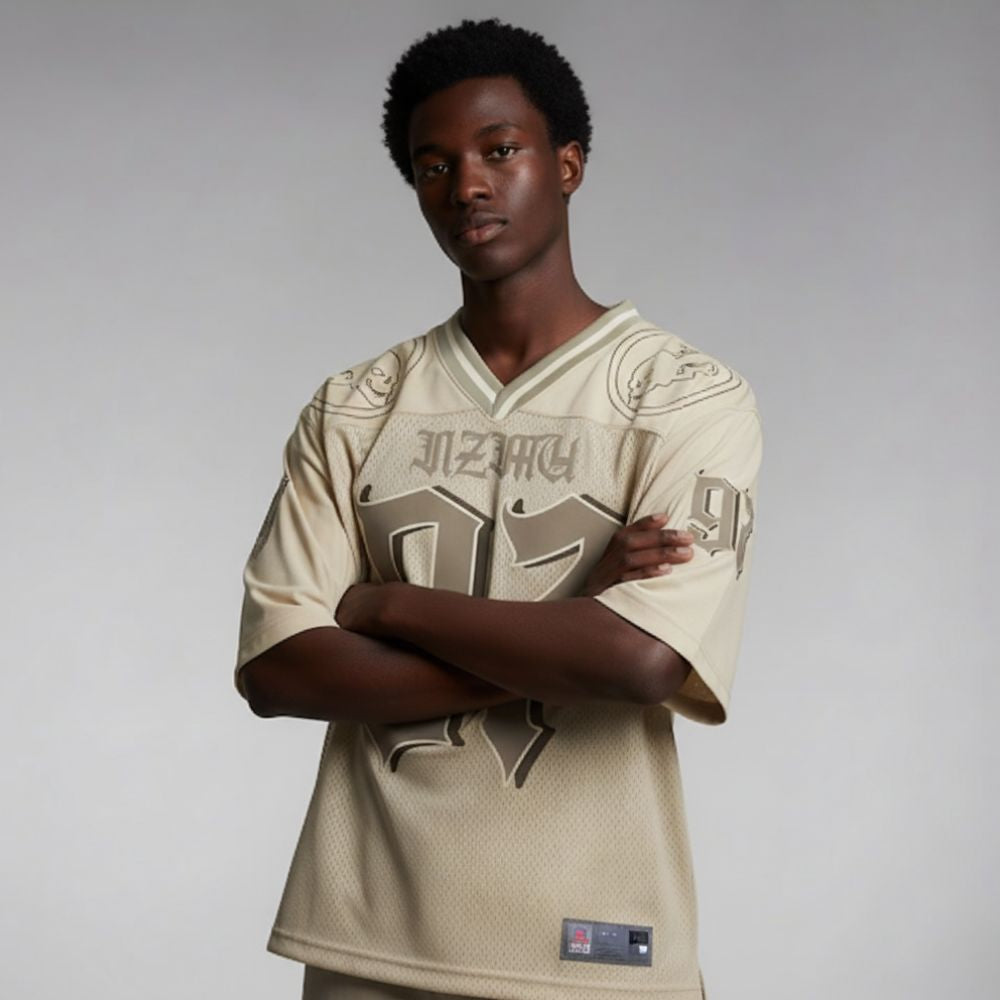 Person wearing a beige sports jersey with branding on a plain background