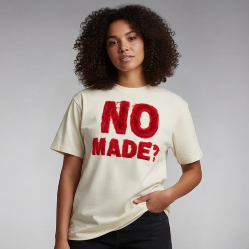 Person wearing a white t-shirt with red text 'NO MADE?' on a plain background