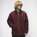 Person wearing a maroon jacket with a brand logo on a white background
