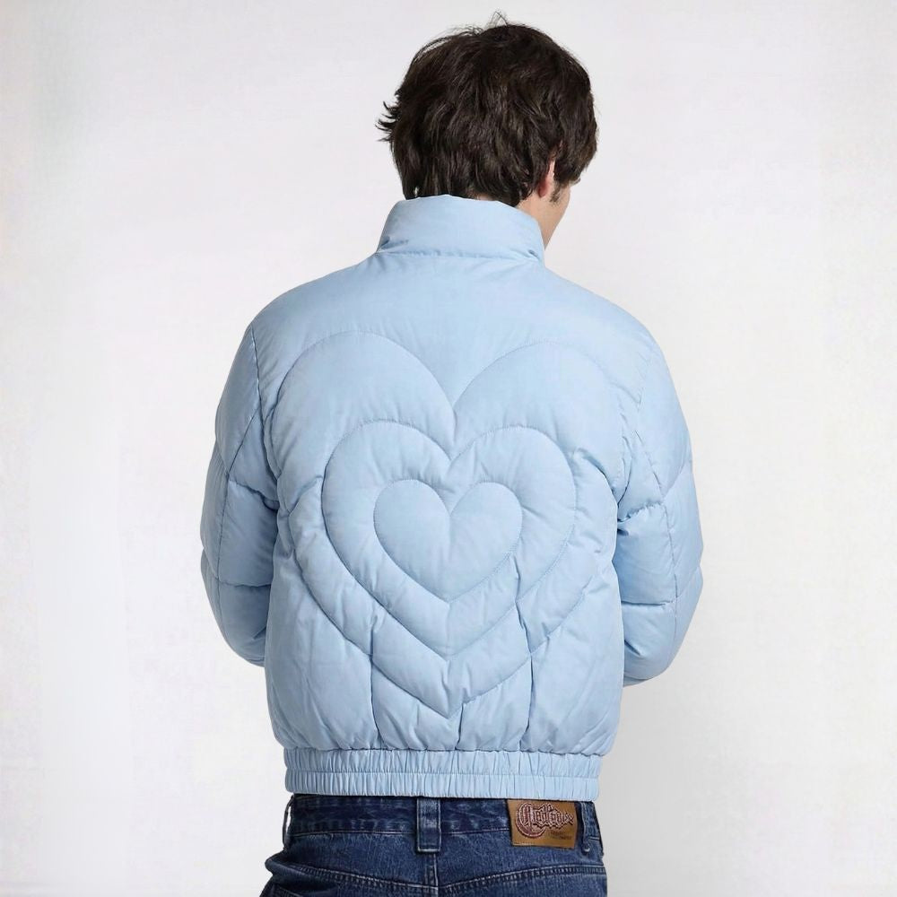 Person wearing a light blue quilted jacket with a heart pattern on the back against a white background