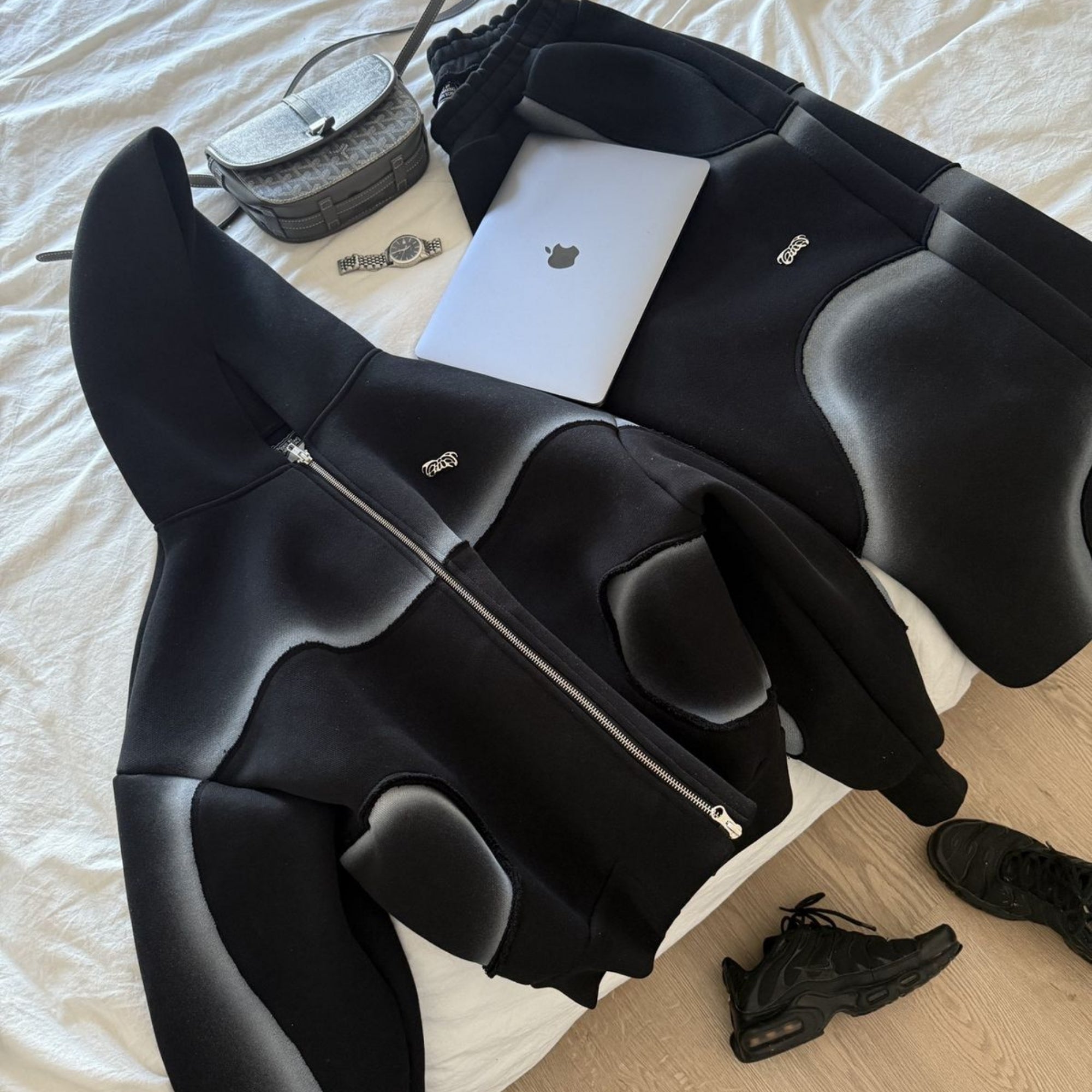 Black high-heeled shoes on a bed with a small bag and book.