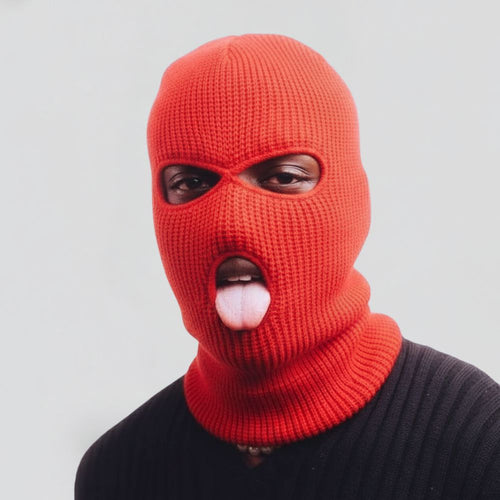 Person wearing a red ski mask with a white object in their mouth on a light gray background